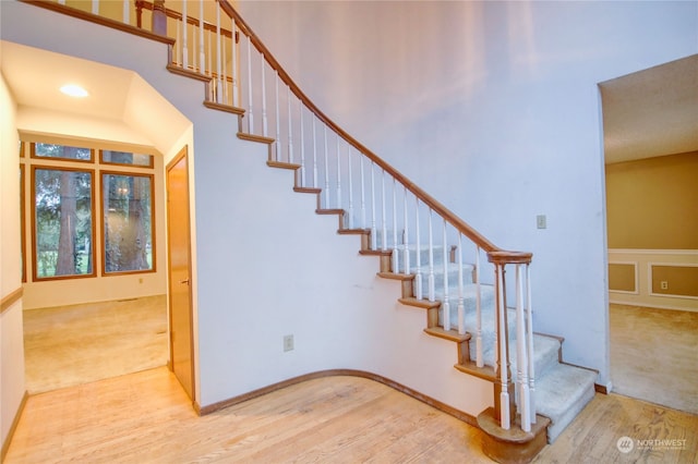 staircase featuring a towering ceiling and hardwood / wood-style floors