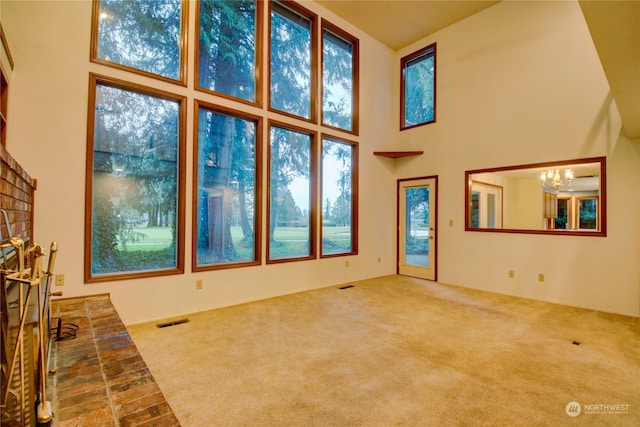 unfurnished living room featuring a towering ceiling, a chandelier, and carpet