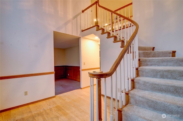 stairway with wood-type flooring and a high ceiling