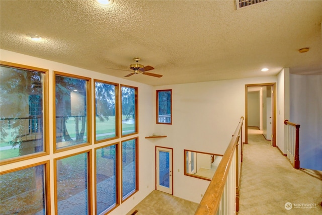 hallway with light colored carpet and a textured ceiling