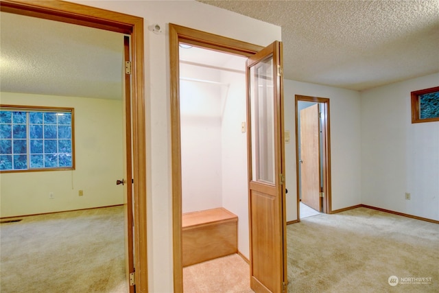 corridor featuring light carpet and a textured ceiling