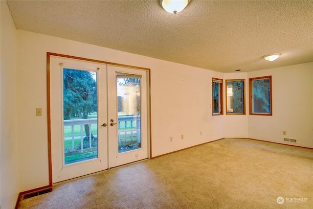 empty room featuring carpet flooring, a textured ceiling, and french doors