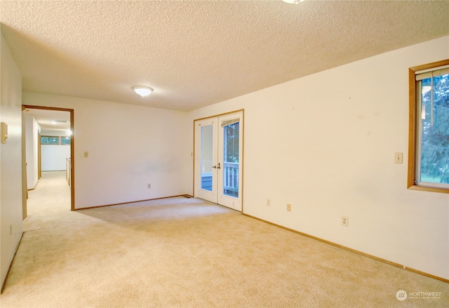 carpeted spare room featuring french doors and a textured ceiling