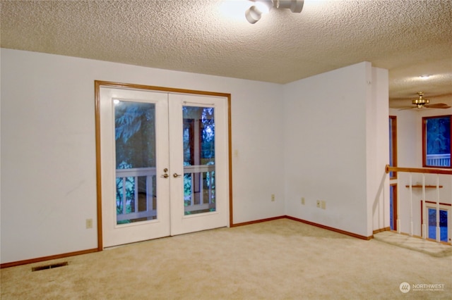 empty room with french doors, a textured ceiling, and carpet flooring