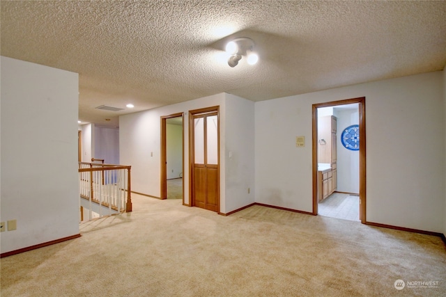 empty room with light carpet and a textured ceiling