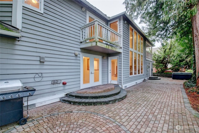 property entrance featuring a hot tub, a balcony, and a patio area