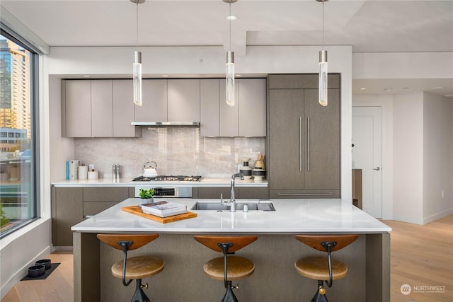 kitchen featuring sink, decorative light fixtures, gray cabinets, and a kitchen breakfast bar