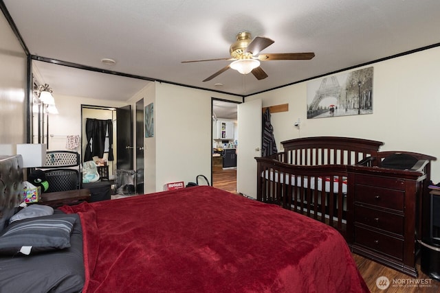 bedroom with dark wood-style floors, crown molding, and a ceiling fan