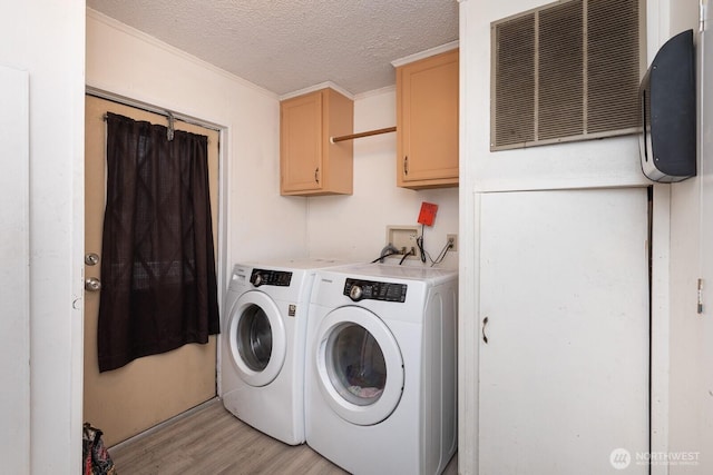 washroom with a textured ceiling, visible vents, washer and dryer, cabinet space, and light wood finished floors