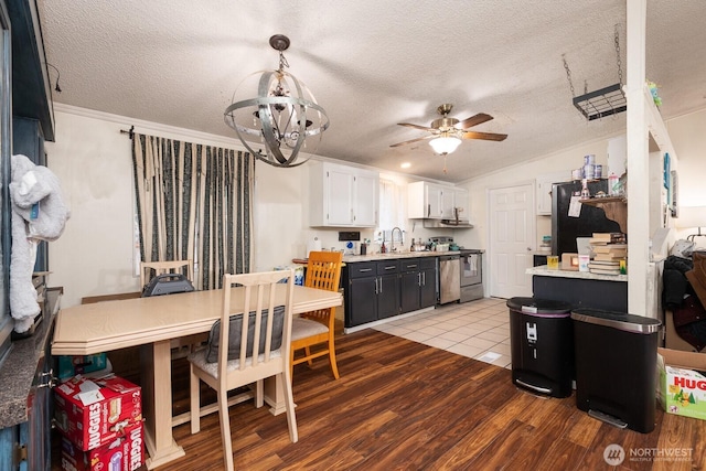 kitchen with decorative light fixtures, stainless steel stove, white cabinets, a sink, and dark cabinets