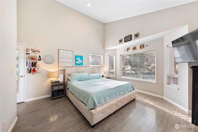 bedroom with dark wood-type flooring and a high ceiling