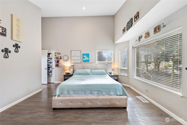 bedroom featuring a high ceiling and dark hardwood / wood-style flooring