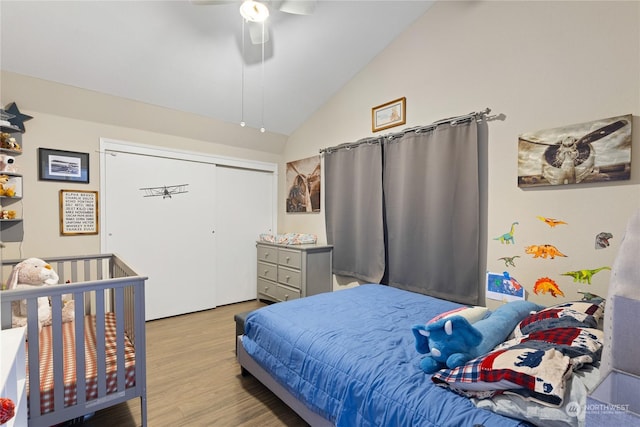 bedroom featuring ceiling fan, light hardwood / wood-style floors, vaulted ceiling, and a closet