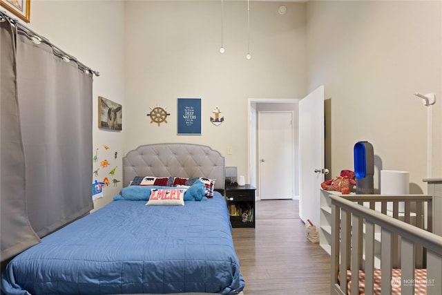 bedroom with hardwood / wood-style floors and a high ceiling