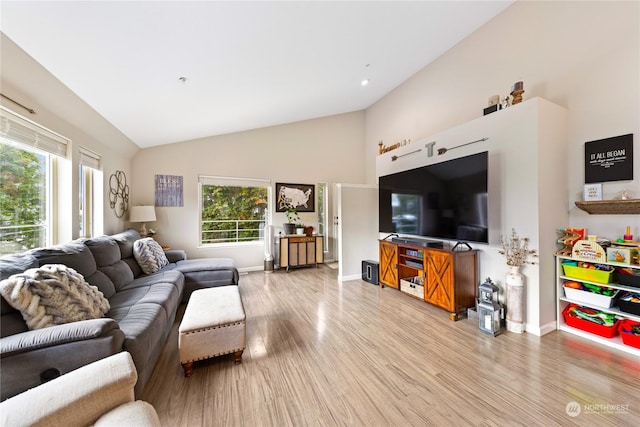 living room featuring vaulted ceiling, light wood-type flooring, and a wealth of natural light