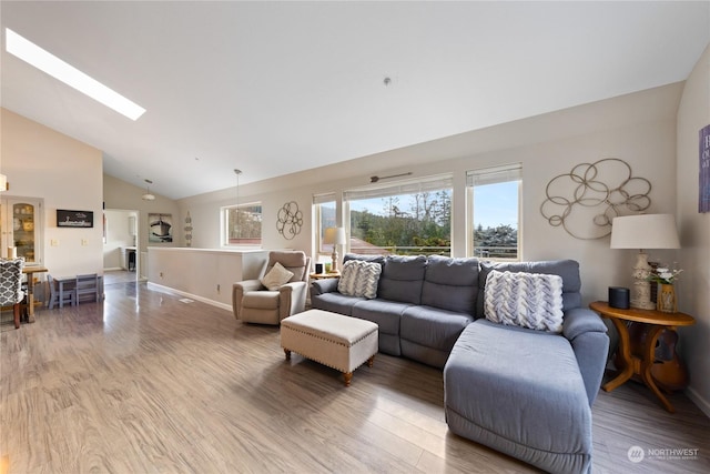 living room featuring hardwood / wood-style flooring, a skylight, and high vaulted ceiling