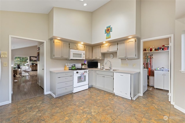 kitchen with sink, white appliances, and high vaulted ceiling