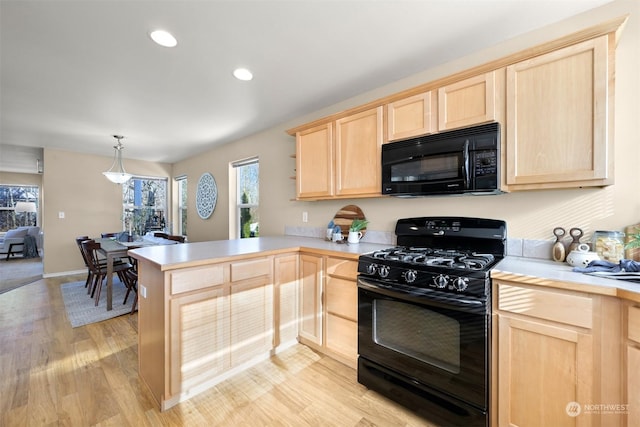 kitchen featuring black appliances, hanging light fixtures, kitchen peninsula, light brown cabinets, and light hardwood / wood-style flooring