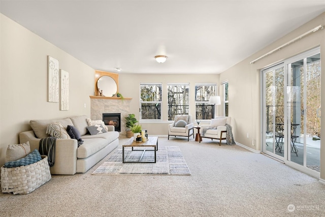 living room featuring a tile fireplace, carpet floors, and a wealth of natural light