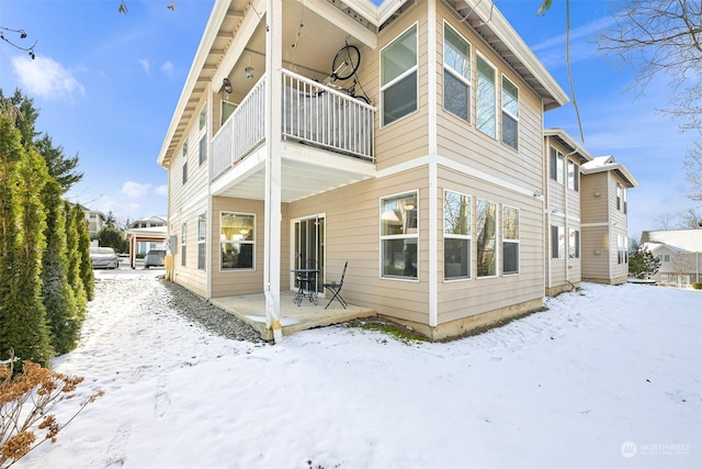 snow covered back of property with a balcony