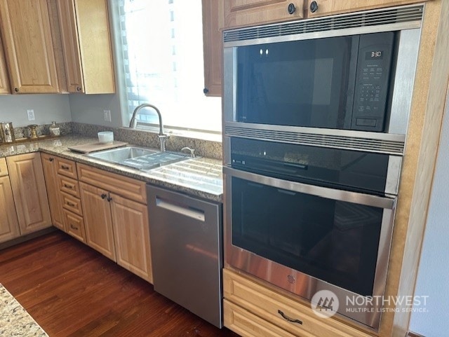 kitchen with appliances with stainless steel finishes, light brown cabinetry, sink, dark hardwood / wood-style flooring, and light stone countertops