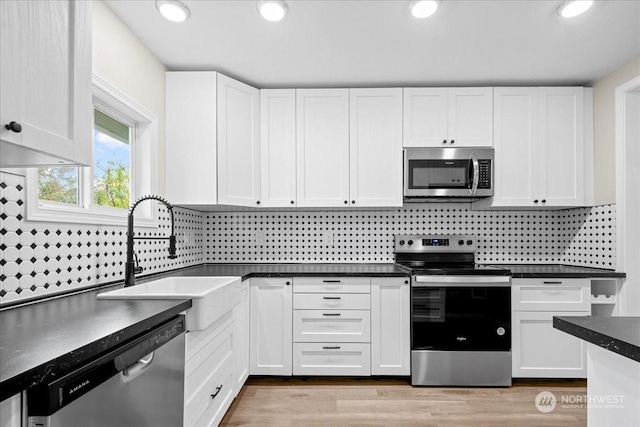 kitchen with sink, appliances with stainless steel finishes, backsplash, light hardwood / wood-style floors, and white cabinets