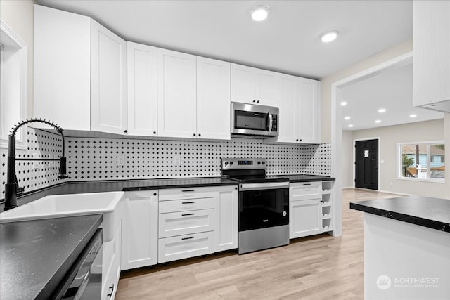 kitchen with sink, white cabinets, decorative backsplash, stainless steel appliances, and light hardwood / wood-style flooring