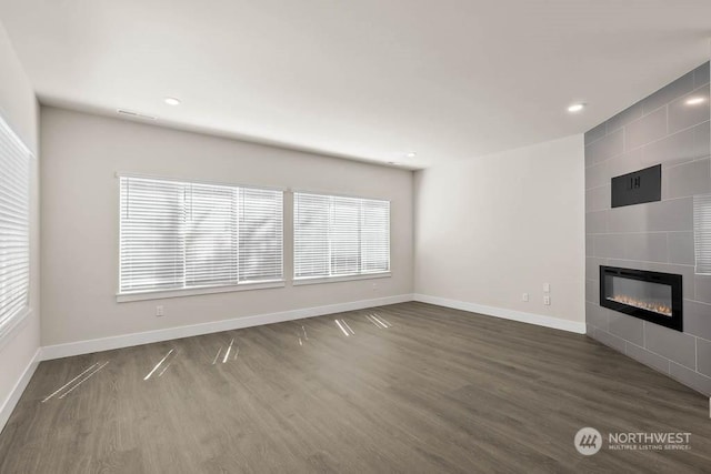 unfurnished living room featuring dark hardwood / wood-style floors and a tiled fireplace