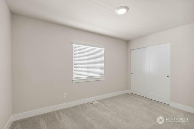 unfurnished bedroom featuring light carpet and a closet