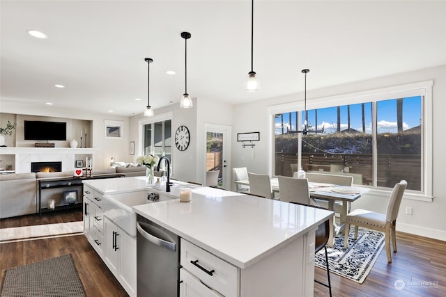 kitchen featuring decorative light fixtures, stainless steel dishwasher, and a center island with sink