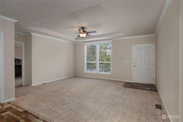 interior space with a tray ceiling, carpet floors, ornamental molding, and ceiling fan