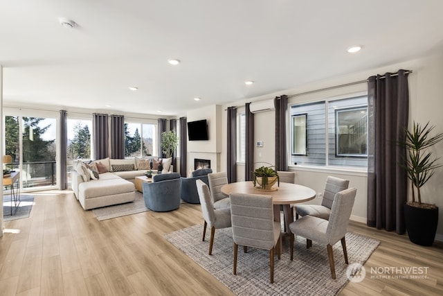 dining room with an AC wall unit and light hardwood / wood-style floors