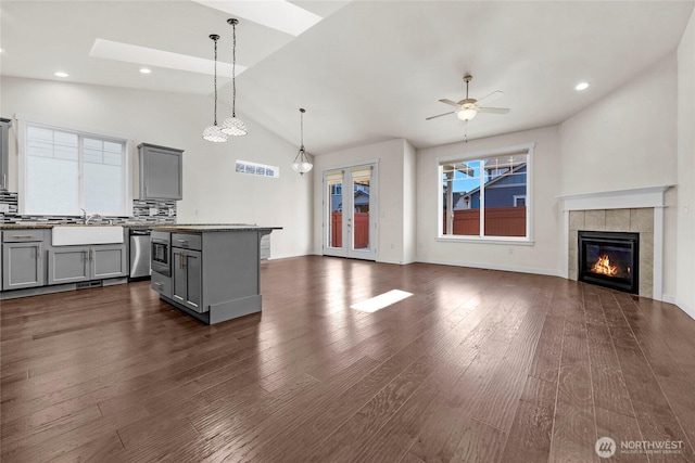 kitchen featuring a sink, open floor plan, stainless steel dishwasher, gray cabinets, and dark wood-style floors