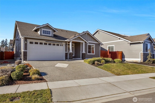 craftsman-style house with a garage, fence, driveway, stone siding, and board and batten siding