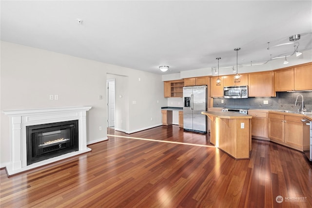 kitchen featuring sink, tasteful backsplash, a center island, hanging light fixtures, and appliances with stainless steel finishes