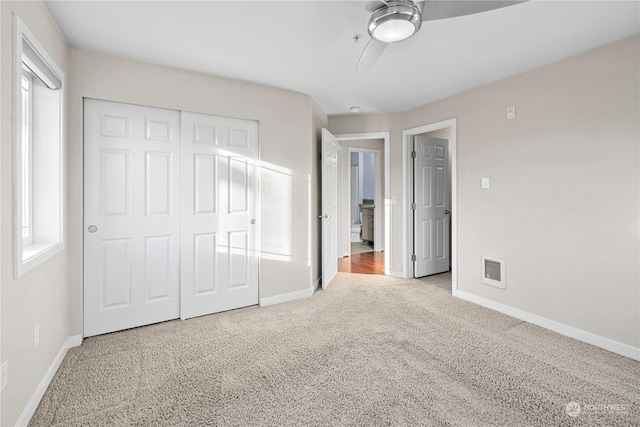 unfurnished bedroom featuring ceiling fan, light carpet, and a closet