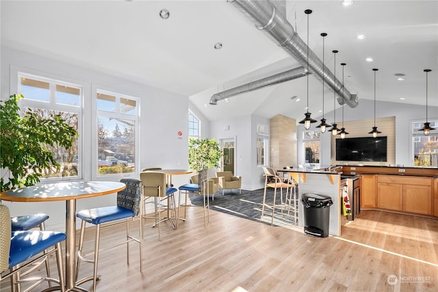 kitchen featuring pendant lighting, lofted ceiling, a breakfast bar, and light hardwood / wood-style flooring