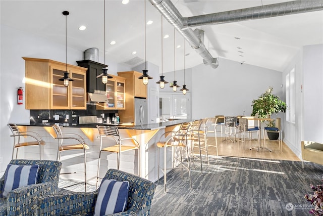 kitchen featuring vaulted ceiling with beams, stainless steel fridge, kitchen peninsula, pendant lighting, and decorative backsplash