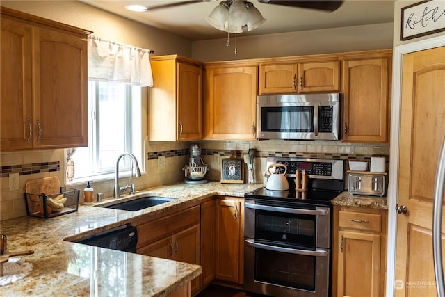 kitchen featuring sink, light stone counters, appliances with stainless steel finishes, ceiling fan, and backsplash