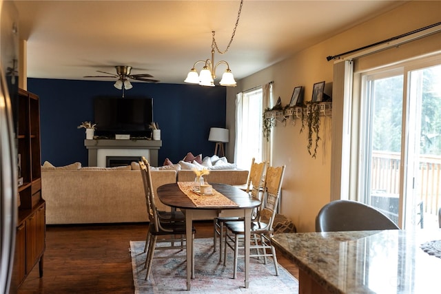 dining area with ceiling fan with notable chandelier and dark hardwood / wood-style floors