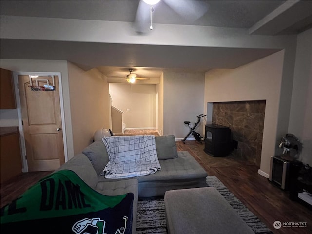 living room featuring dark hardwood / wood-style flooring, ceiling fan, and a wood stove