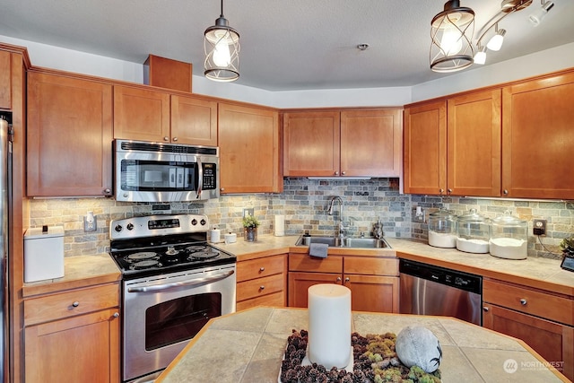 kitchen featuring tasteful backsplash, stainless steel appliances, decorative light fixtures, and sink