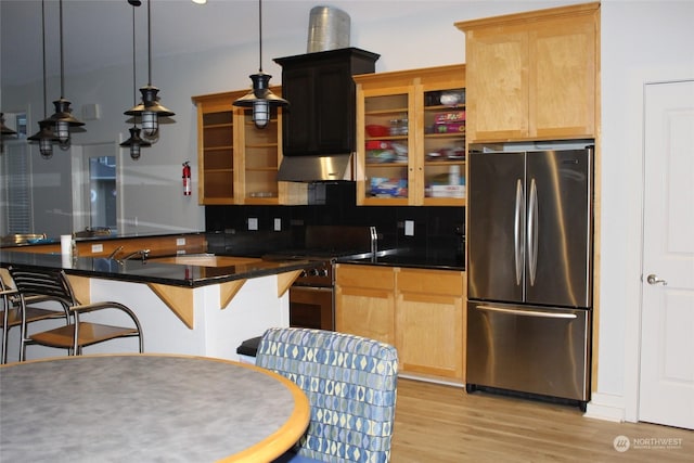 kitchen featuring appliances with stainless steel finishes, hanging light fixtures, tasteful backsplash, light hardwood / wood-style floors, and light brown cabinetry