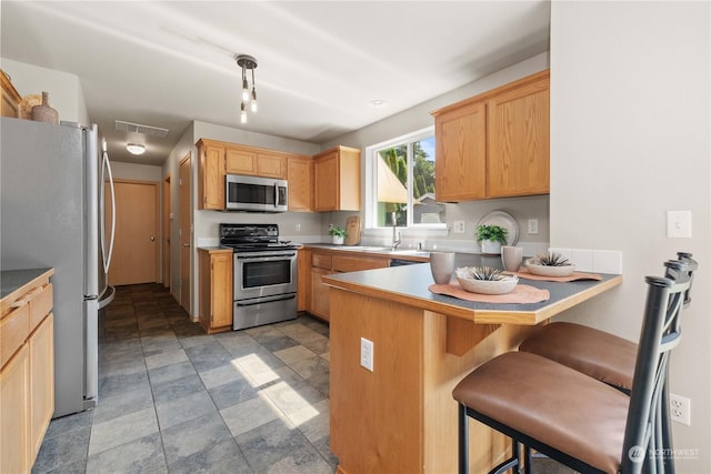 kitchen with sink, a kitchen bar, hanging light fixtures, kitchen peninsula, and stainless steel appliances