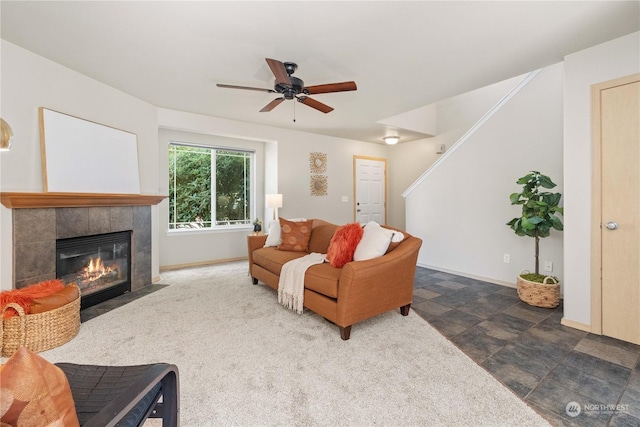 living room featuring ceiling fan and a tiled fireplace