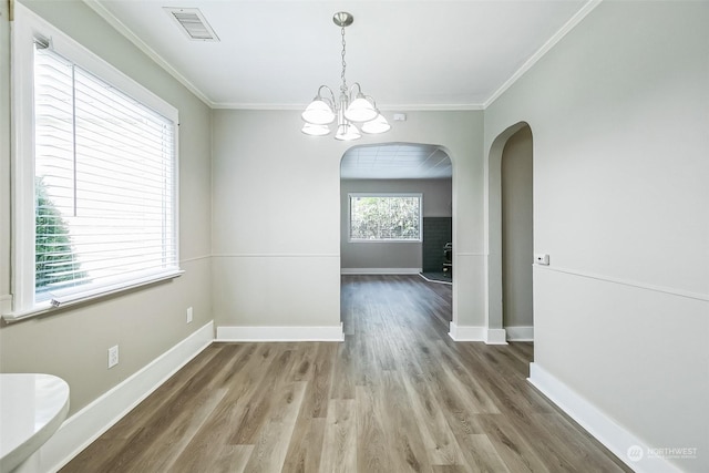 unfurnished dining area featuring crown molding, wood-type flooring, and a chandelier