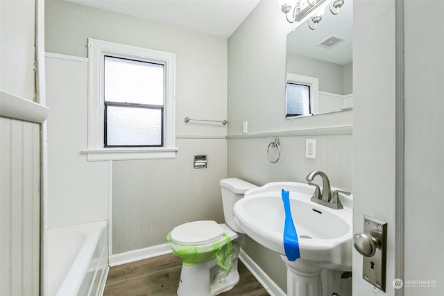 bathroom featuring a bath, hardwood / wood-style flooring, sink, and toilet