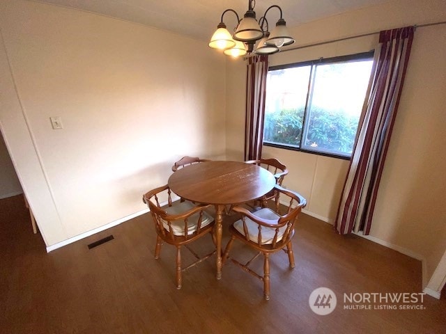 dining area featuring dark wood-type flooring and a chandelier