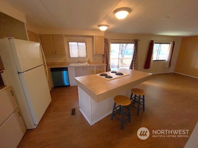 kitchen featuring sink, white appliances, a kitchen breakfast bar, a center island, and light wood-type flooring