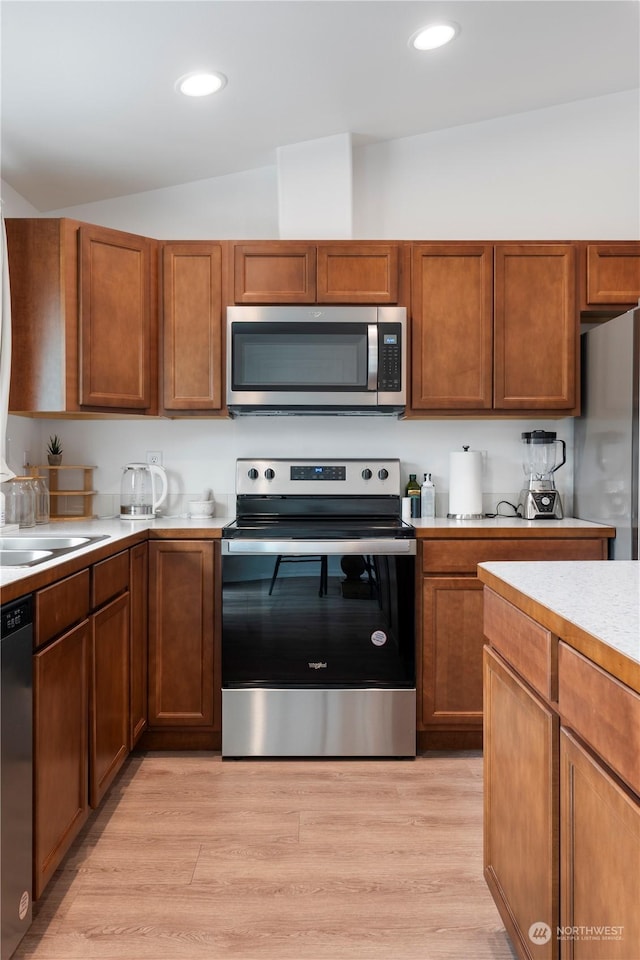 kitchen featuring lofted ceiling, sink, light hardwood / wood-style flooring, and stainless steel appliances